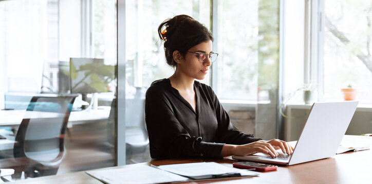 Young businesswoman professional employee using pc doing online banking analysing at workplace. Latin hispanic middle age business woman working on laptop computer in modern office. Banner, copy space
