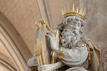 A fragment of a biblical story. King David's head in a golden crown, hands on harp strings