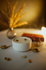 A large candle in a white flowerpot is burning.