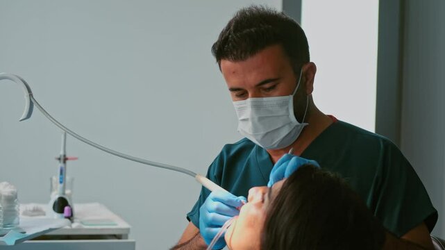 Professional dentist treating a patient in a modern clinic. The patient sits with an open mouth as the dentist drills and cleans teeth with water, ensuring proper dental care and hygiene.