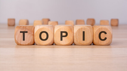 the text TOPIC is written on wooden blocks on a brown background