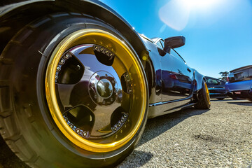 Perspective view of a black car with large golden rims in the front