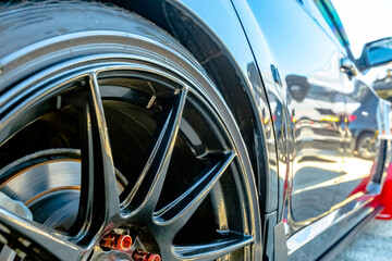 Tires with black rims on a black car with red bolts