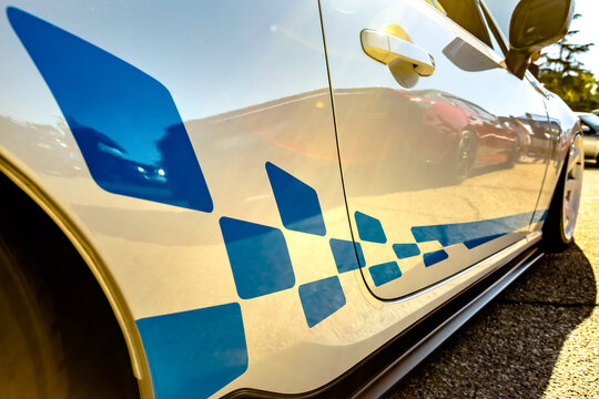 Racing decals on white car with golden reflection on the car handle