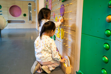 Two young girls are playing with a toy in a room