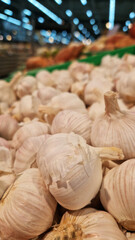 Garlic close up in supermarket. Lots of garlic in plastic green box on market stall. Garlic in green plastic box at farmers market. Garlic for sale in store. Display of fresh produce for sale