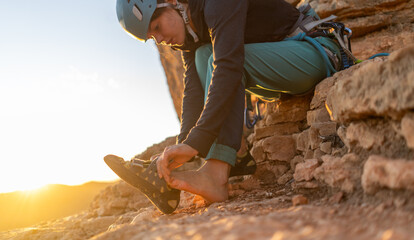 A young girl puts on special climbing shoes on her legs before climbing outdoor training, hands and feet close-up. A woman leads an active lifestyle, is involved in mountaineering and rock climbing.