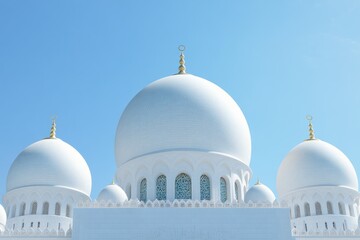 Fototapeta premium Three white domes of a mosque against a clear blue sky.