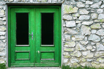 Eine alte Tür an einem Steinhaus in grün und schwarz