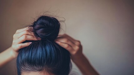 Fototapeta premium Woman Tying Her Hair into a Loose Bun for Nighttime Skincare Routine