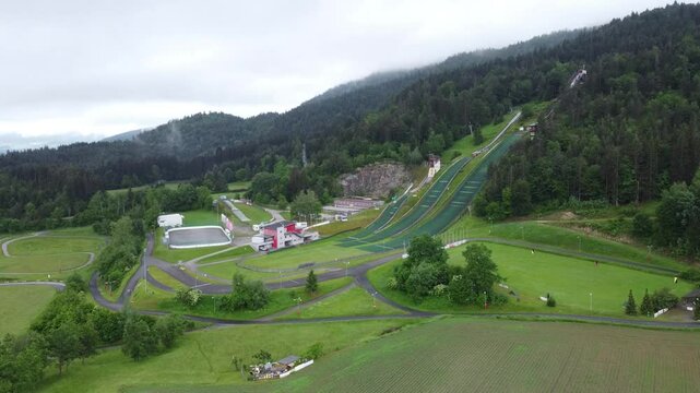 Ski jumps at villacher alpen arena. Drone aerial view of ski jumps at villach in spring, green grass and no snow. overview with camera zooming in or panning