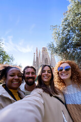 Multiracial group of happy tourists taking a selfie in Barcelona with sagrada familia in the...