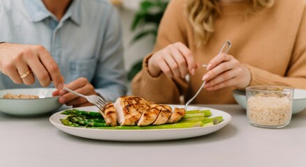 Caucasian young adults enjoying grilled chicken and asparagus meal together
