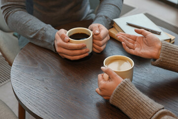 Colleagues talking during coffee break at wooden table in cafe, closeup