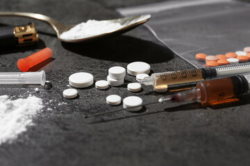 Drug addiction. Pills, syringes and spoon with powder on gray textured table, closeup