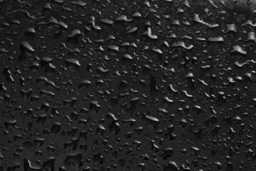 Water drops on dark grey glass surface, top view