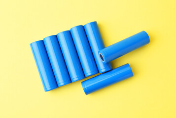 Many AA cell batteries on yellow background, top view