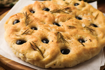 Delicious focaccia bread with olives and rosemary on table, closeup