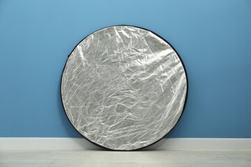 One light reflector near blue wall indoors. Photo studio equipment