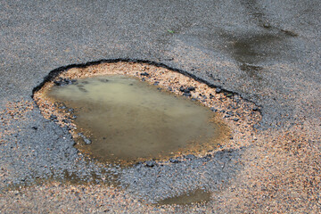 Close up of a pot hole in a road filled with water