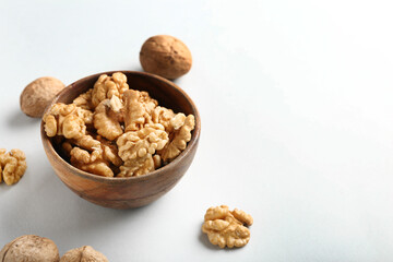 Bowl of tasty walnuts on white background