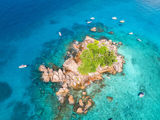 Tiny island surrounded by clear, shallow waters and rocky formations. Seychelles.