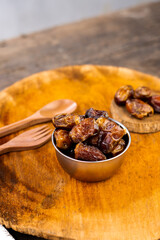 Delicious dry dates, popular fruit dates during the month of Ramadan on a round wooden board with wooden spoon and fork