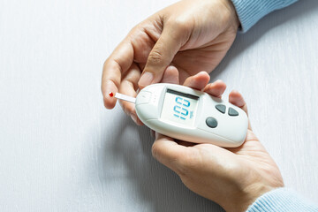 Woman's hands checking diabetes and hyperglycemia with digital blood sugar meter. Healthcare and medical concept	