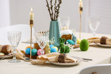 Table setting with Easter cakes, painted eggs and willow branches in room, closeup