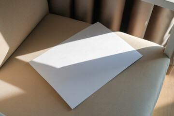 blank paper mockup on elegant soft armchair , shadow overlay, morning light