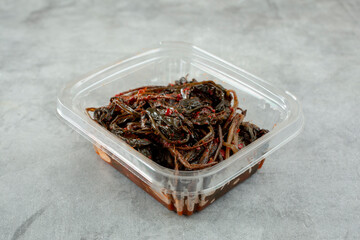 A view of a plastic container of dandelion kimchi.