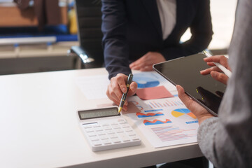 Close-up of two businesswomen working at desk discussing business strategies, analyzing financial charts, planning marketing plans and using laptop to drive business growth in professional office