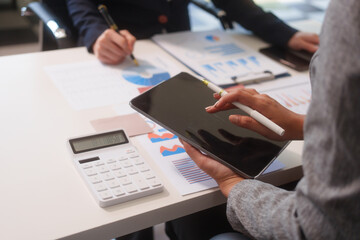 Close-up of two businesswomen working at desk discussing business strategies, analyzing financial charts, planning marketing plans and using laptop to drive business growth in professional office