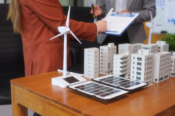Two businesswomen working at desks and discussing sustainable urban development with emphasis on...