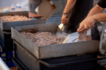 A view of a chef cooking beef on a griddle, seen at a local food festival.