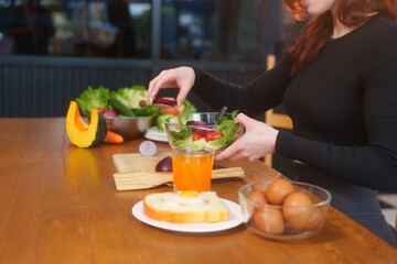 A white woman in workout clothes makes vegetable and fruit juice using a blender on the kitchen...