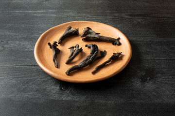 A view of several black trumpet mushrooms, on a clay plate.