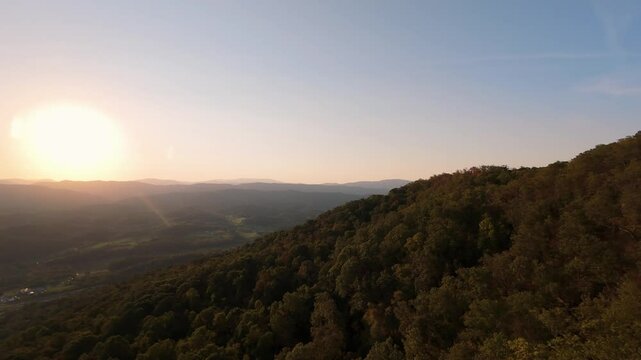 Drone View of Rolling Hills at Sunset breathtaking aerial view of lush green hills bathed in warm golden sunlight as sun sets over horizon, creating peaceful scenic landscape Canada mountain sunrise