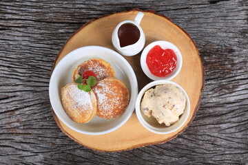 A set of snacks and sweets arranged on a wooden tray, including bread, jam and ice cream 
