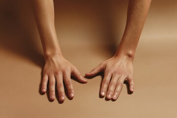 Two human hands resting flat on a neutral colored surface