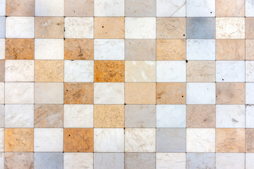 Textured marble tile pattern with alternating white and beige square tiles showing natural imperfections and subtle color variations