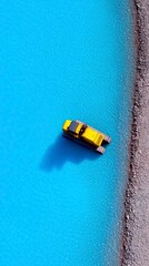 Fototapeta premium Yellow Tractor Vehicle in Azure Waterway Alongside Stony Shoreline Overhead View with Reflective Shadow