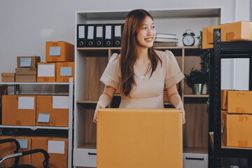 Asian SME business women use laptop computer checking customer order online shipping boxes at home....
