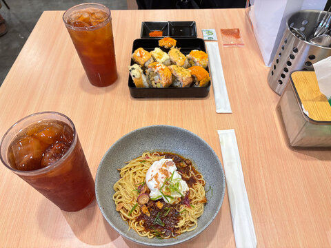 dinner with chili oil noodles, sushi variants, and fresh iced tea ready to enjoy