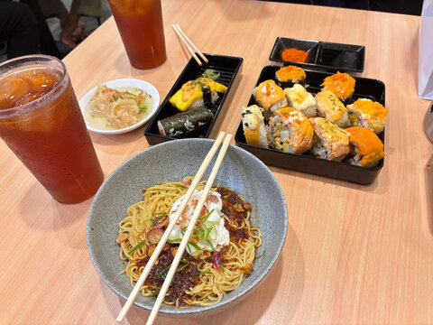 dinner with chili oil noodles, sushi variants, and fresh iced tea ready to enjoy