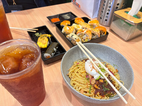 dinner with chili oil noodles, sushi variants, and fresh iced tea ready to enjoy