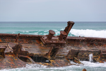 Rusty bollards and iron hull plates with the deteriorating deck timbers of the wreck of the steam...