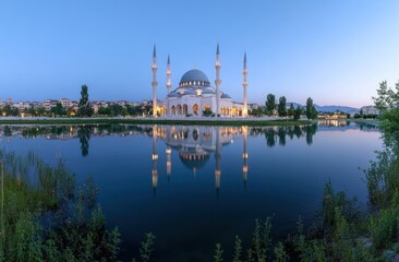 Obraz premium Majestic mosque reflected in tranquil water at dawn.