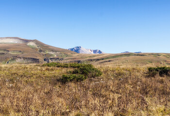 panorama of the mountainous area in the autumn, yellowed slopes, remnants of meadow grass and dried plants