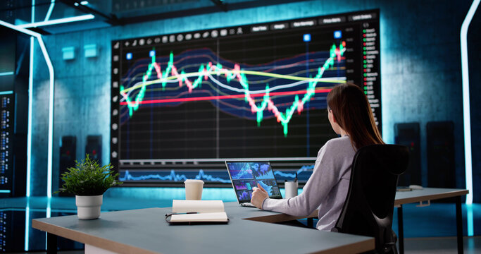 Female Stock Analyst Analyzing Data on Computer Screens